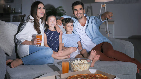 Happy family watching TV on sofa at night
